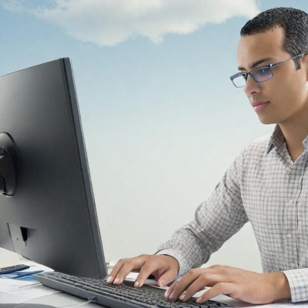 Homme à lunette réalisant une formation e-learning de bureautique Homme en chemise à carreaux tapant sur un clavier, regardant un écran d'ordinateur.