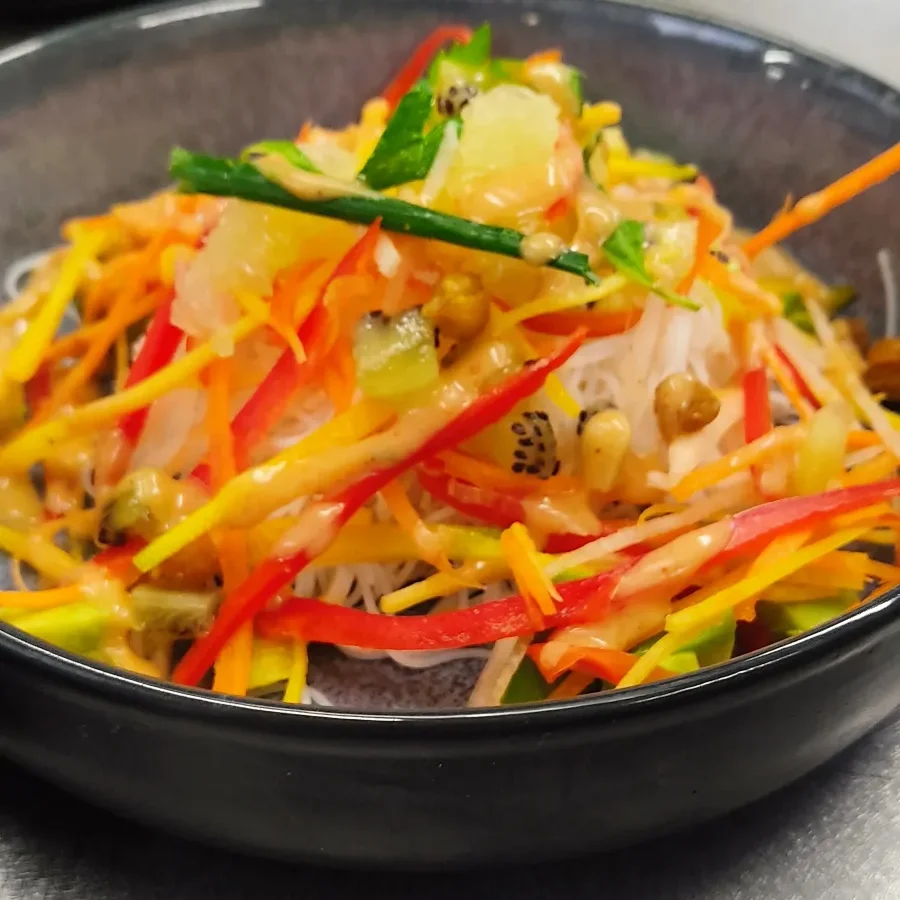 Salade de nouilles avec légumes colorés et sauce épicée.