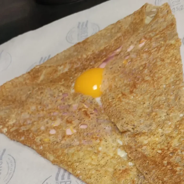 Galette bretonne croustillante avec un œuf au centre, servie sur du papier réalisée lors de notre formation en Bretagne