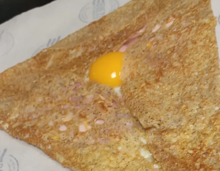 Galette bretonne avec un œuf au centre, garnie de jambon et de fromage.