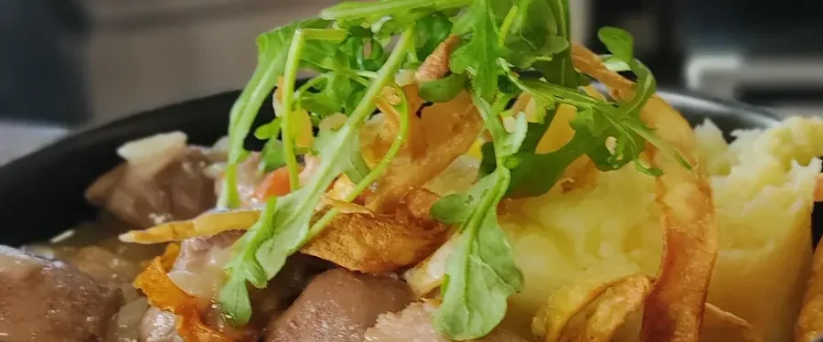 Sauté de porc à la bière Plat de viande avec purée, garnie de salade et de fines herbes.